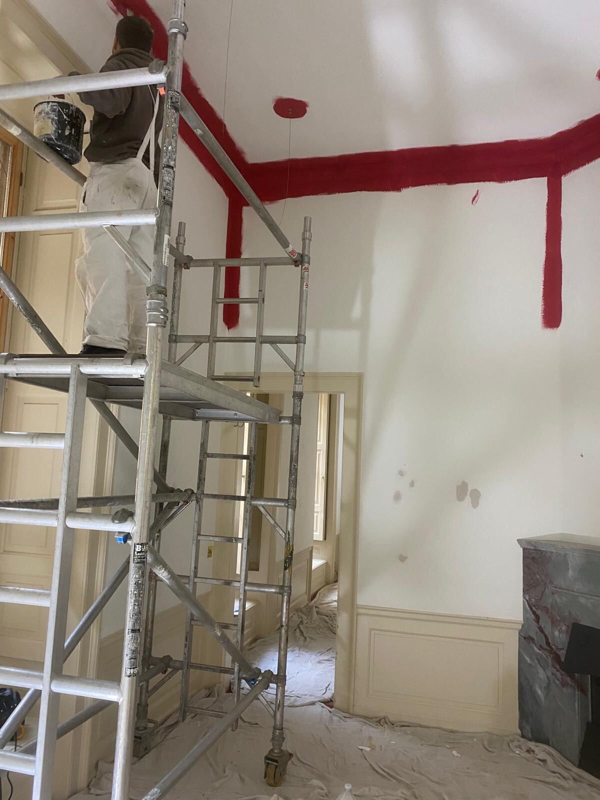 Brierty decorator cutting in deep red heritage paint from scaffold tower at Blenheim Palace