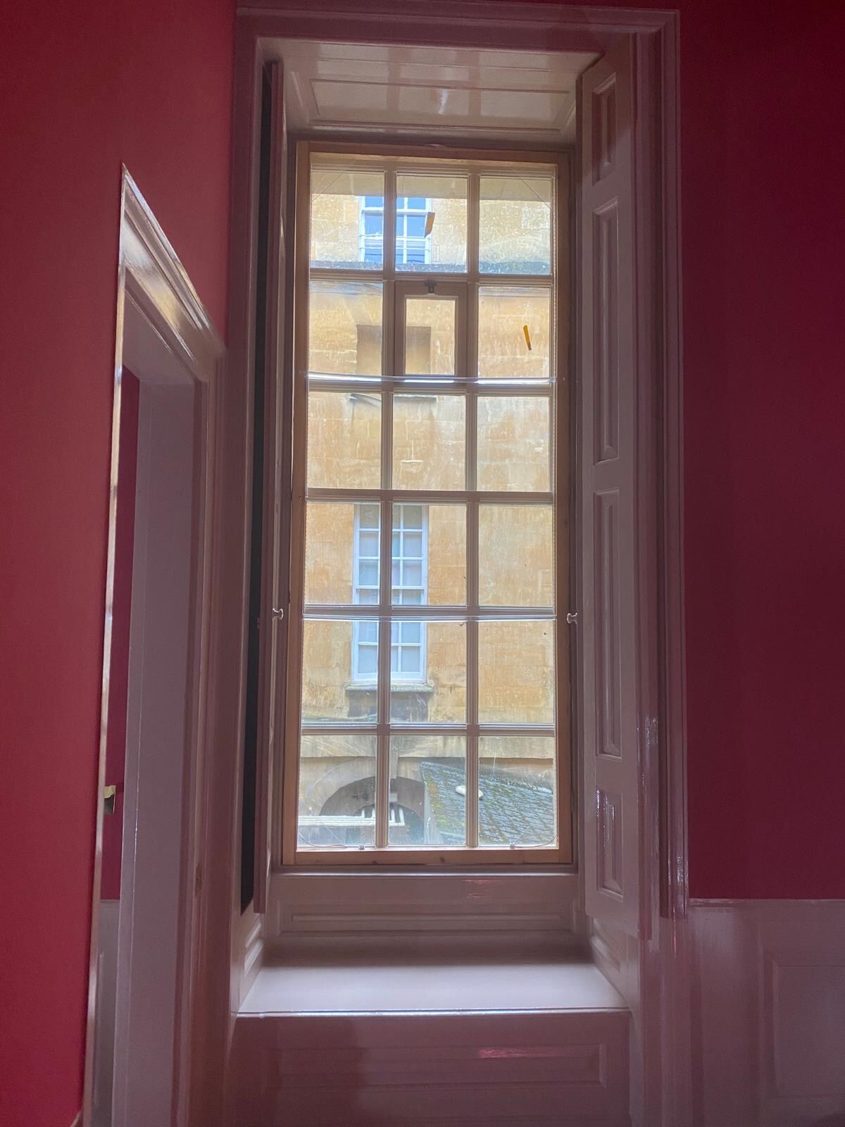 Heritage sash window framed by deep red walls in a Blenheim Palace state room