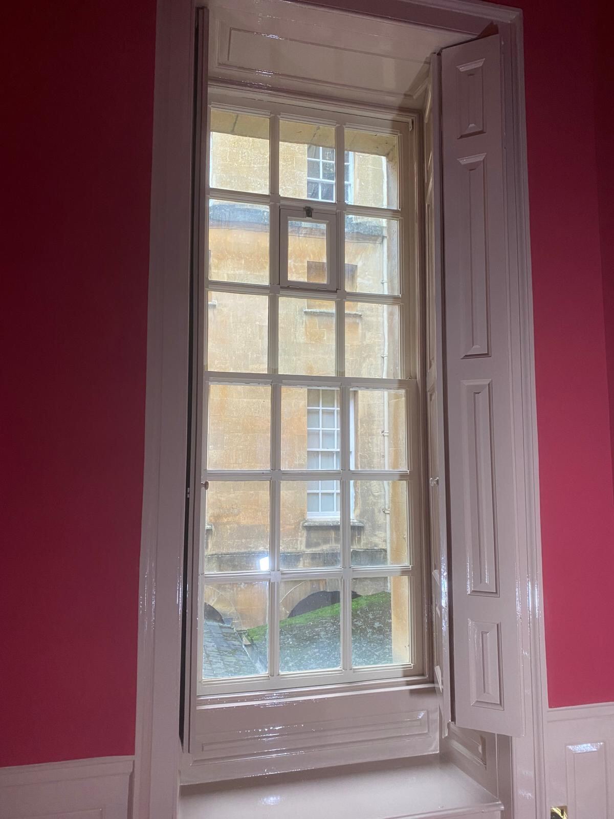 Tall Georgian sash window with panelled shutters overlooking Blenheim Palace courtyard