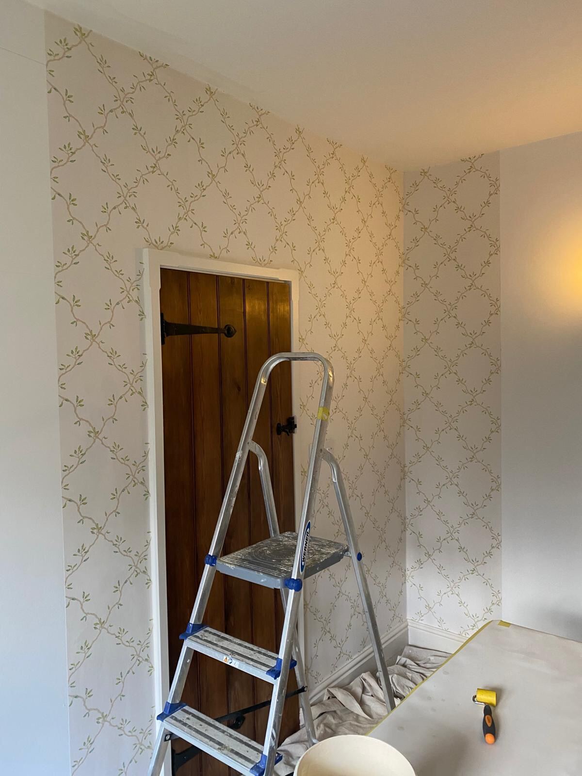 Green leaf-trellis wallpaper cut tightly around an oak door, executed for Elizabeth Cleall Interiors